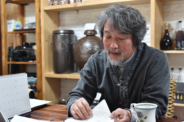 김기엽 소장이 전통주 빚는 과정을 정리한 공책들을 보여주고 있다.