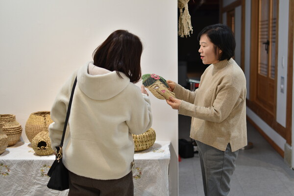 이준희 씨가 관람객에게 짚풀로 엮어서 만든 작품을 하나하나 설명하고 있다.